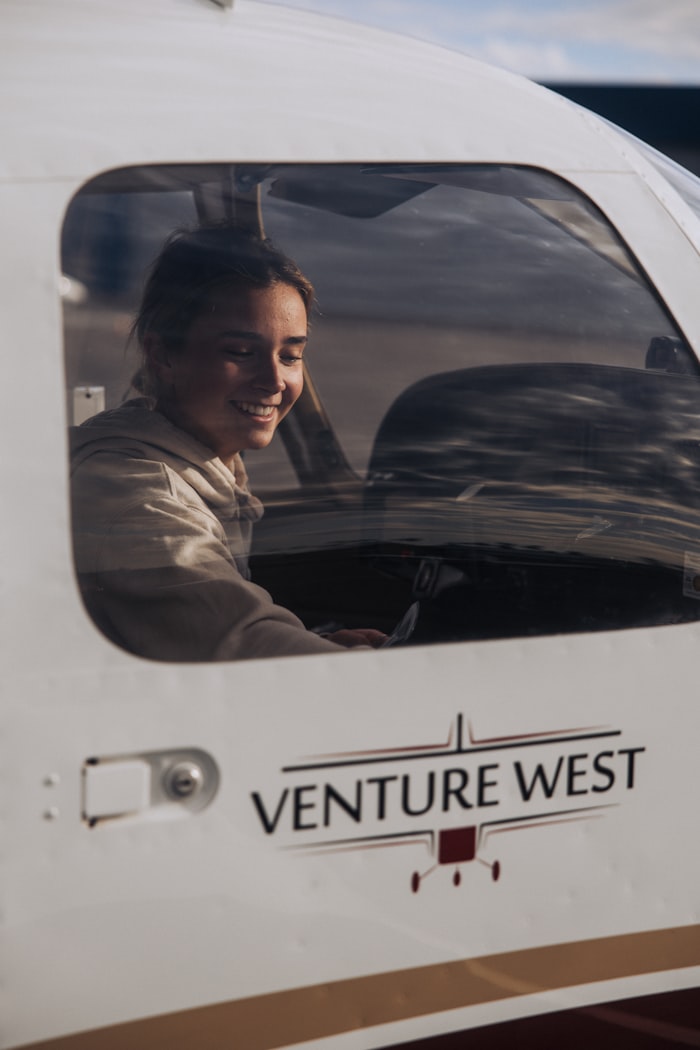 A smiling student pilot in the cockpit of a small training aircraft